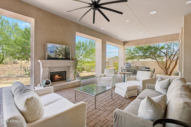 sunroom / solarium with a ceiling fan, a wealth of natural light, and a lit fireplace