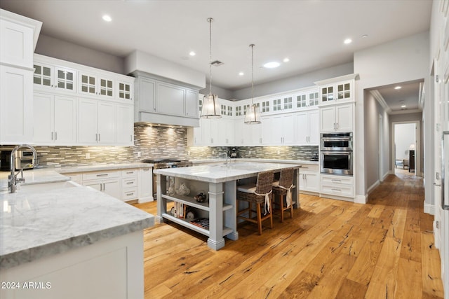 kitchen featuring a center island, stainless steel appliances, light wood-style floors, a sink, and a kitchen breakfast bar