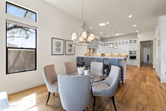 dining area featuring baseboards, recessed lighting, light wood-style flooring, and an inviting chandelier