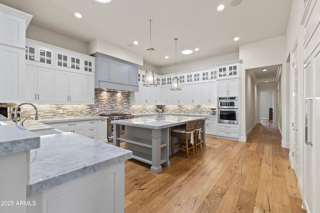 kitchen with white cabinets, light wood-style flooring, a breakfast bar, stainless steel appliances, and a sink