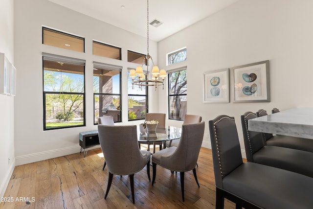 dining room with a chandelier, wood-type flooring, visible vents, and baseboards