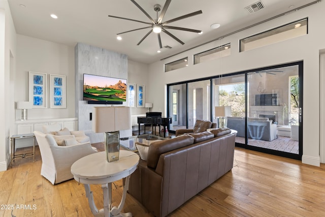 living area featuring light wood-style floors, a fireplace, visible vents, and recessed lighting