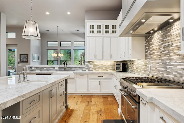 kitchen featuring range hood, double oven range, a sink, and decorative backsplash