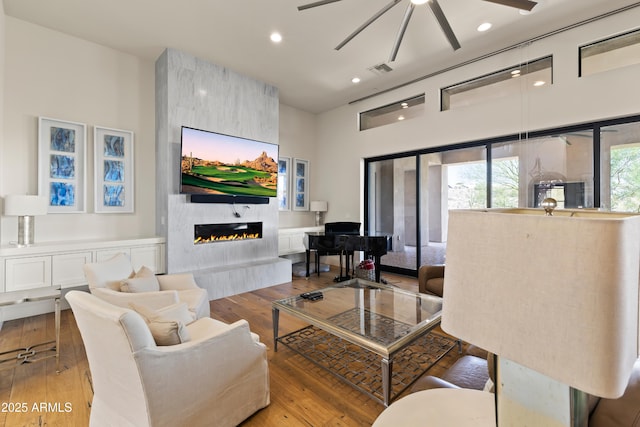 living room with visible vents, a ceiling fan, light wood-style flooring, a fireplace, and recessed lighting