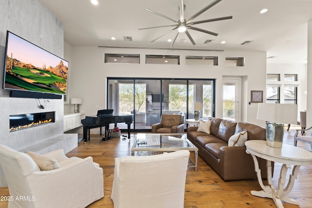 living area with light wood finished floors, plenty of natural light, and a tiled fireplace