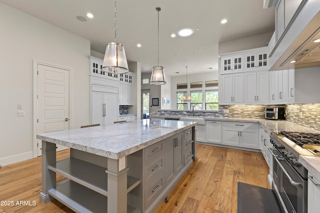 kitchen featuring premium appliances, premium range hood, backsplash, and open shelves