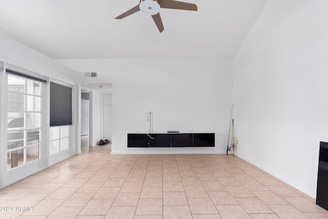 unfurnished living room with ceiling fan, vaulted ceiling, and light tile patterned floors