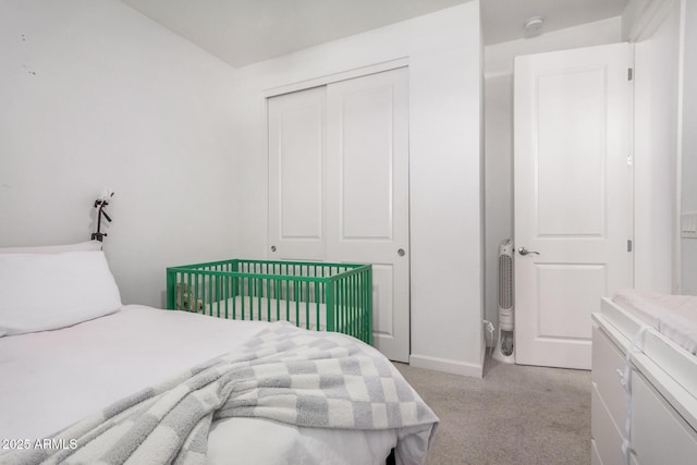 bedroom with light colored carpet, a closet, and baseboards
