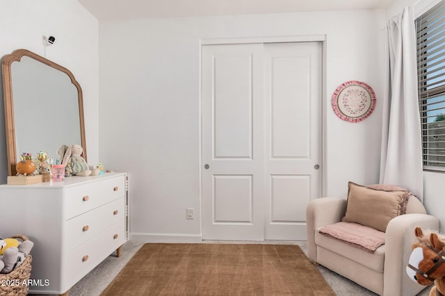 living area featuring light carpet and baseboards