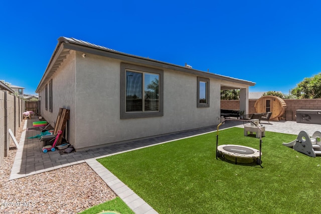 rear view of house with a fire pit, a patio, and stucco siding