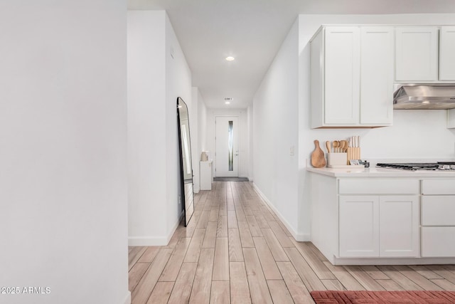 hallway featuring light wood-style floors, baseboards, and recessed lighting