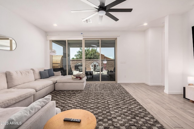 living area with wood finished floors, a ceiling fan, baseboards, and recessed lighting