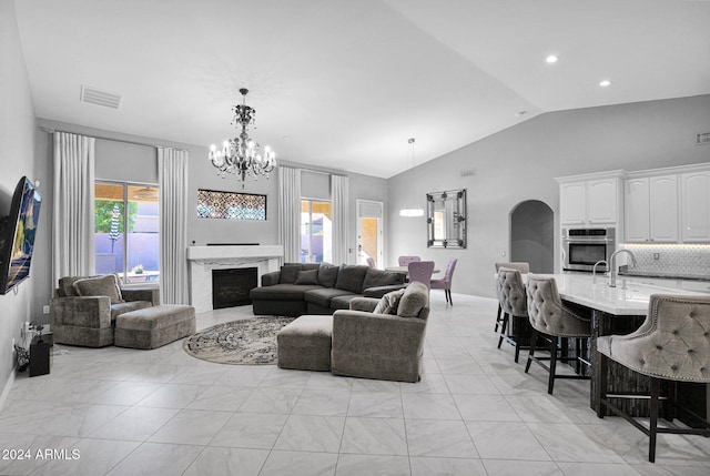 living room featuring vaulted ceiling, a notable chandelier, and a premium fireplace