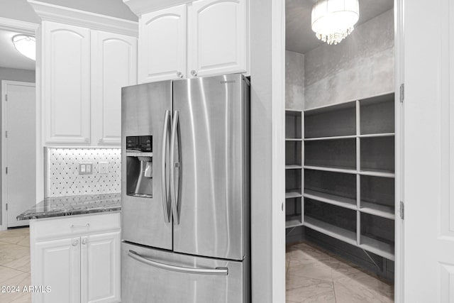 kitchen with stainless steel refrigerator with ice dispenser, white cabinetry, and dark stone counters