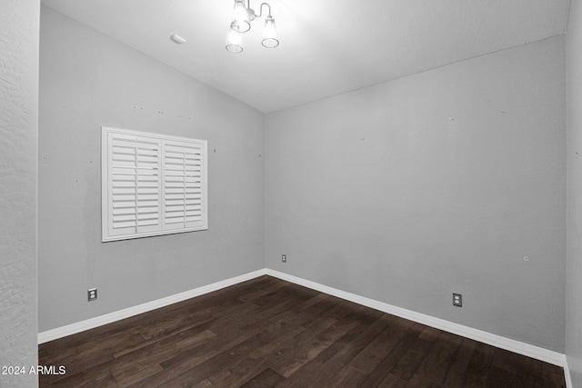 empty room featuring dark wood-type flooring and vaulted ceiling