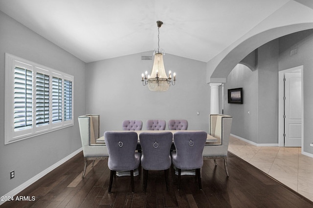 dining space with ornate columns, wood-type flooring, lofted ceiling, and an inviting chandelier