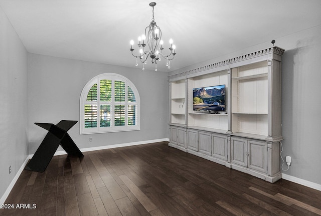 empty room featuring dark wood-type flooring and a chandelier