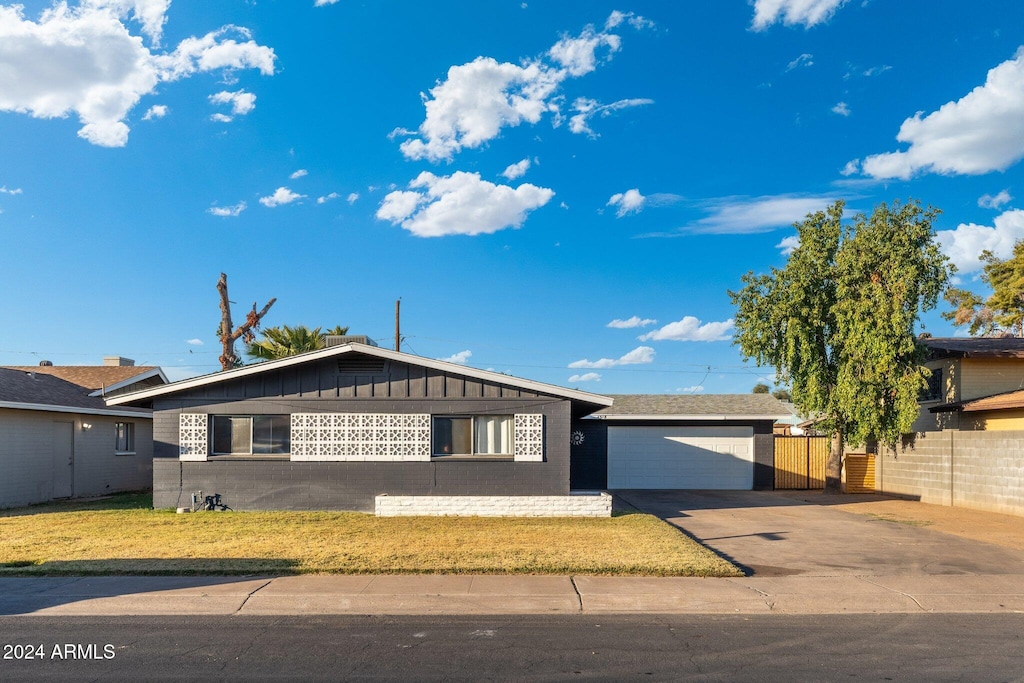 4518 W Rose Ln, Glendale, AZ 85301 - view of front of property featuring driveway, fence, an attached garage, board and batten siding, and a front yard