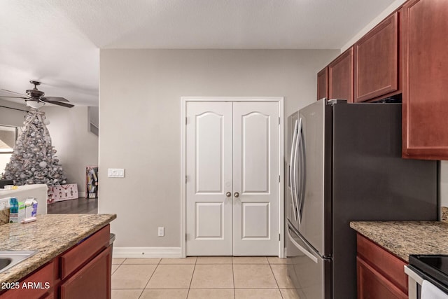 kitchen featuring stainless steel refrigerator, light stone countertops, ceiling fan, and light tile patterned floors