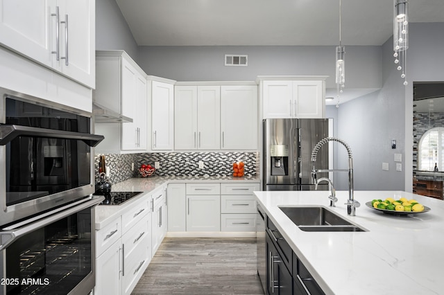 kitchen featuring decorative light fixtures, tasteful backsplash, white cabinetry, sink, and stainless steel appliances