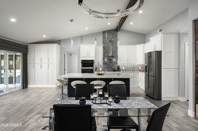 6102 E Nisbet Rd, Scottsdale, AZ 85254 - kitchen with a kitchen bar, appliances with stainless steel finishes, an island with sink, decorative backsplash, and white cabinets