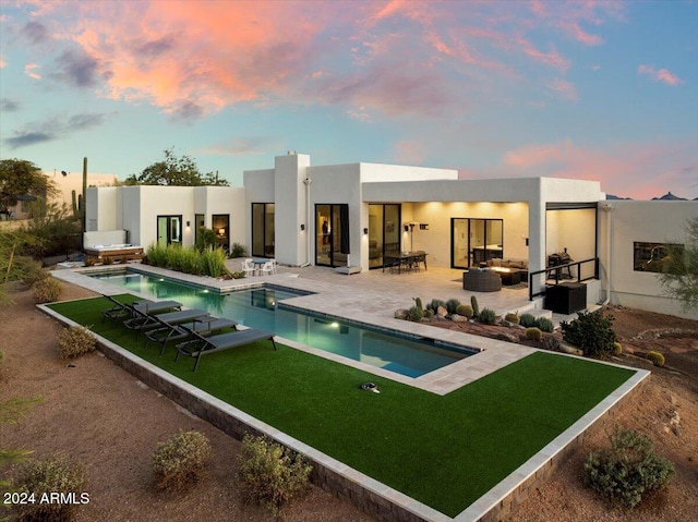 back house at dusk with a yard and a patio area