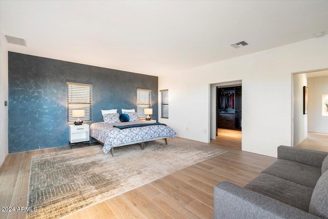 bedroom with a closet, a spacious closet, and wood-type flooring