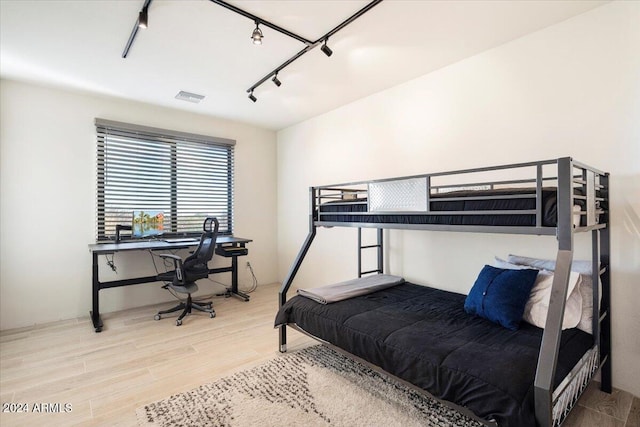 bedroom featuring hardwood / wood-style flooring and track lighting