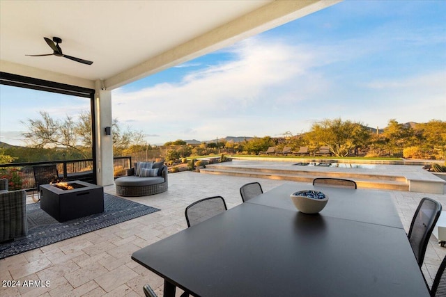 view of patio / terrace featuring ceiling fan and an outdoor living space with a fire pit