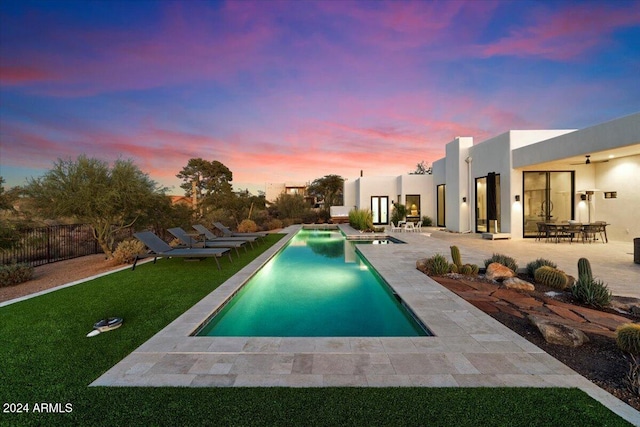 pool at dusk featuring a patio and a yard