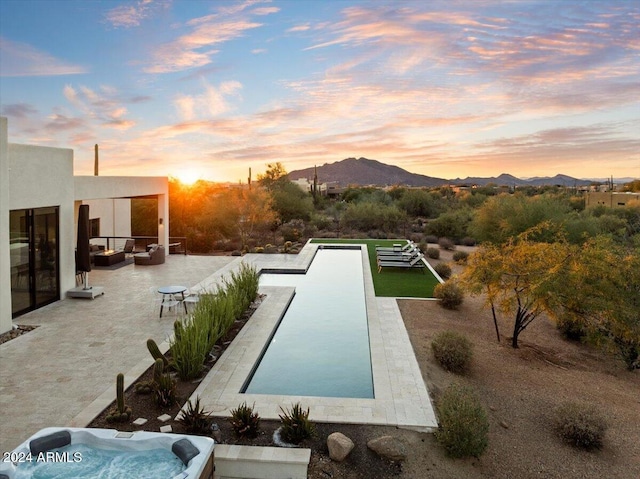 pool at dusk featuring a mountain view and a patio area