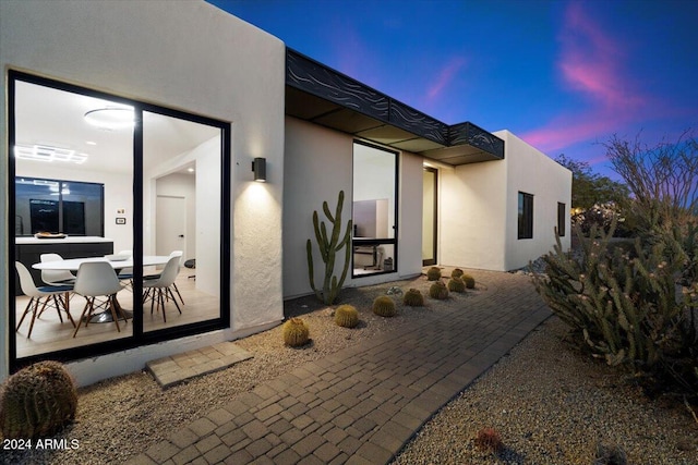 exterior entry at dusk featuring a patio