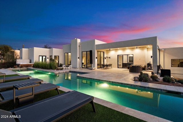 pool at dusk with a patio area