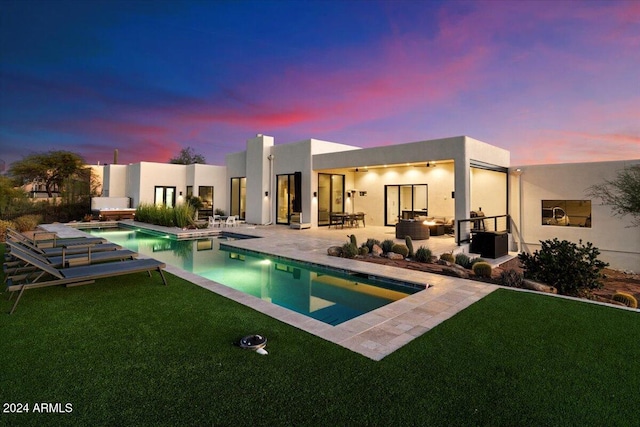 pool at dusk featuring a patio and a yard