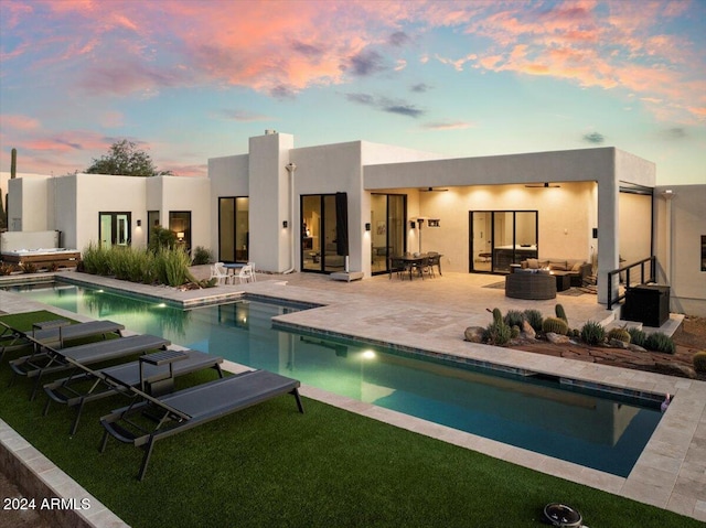 pool at dusk with a patio and a yard