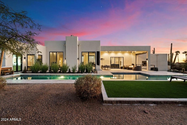 back house at dusk featuring a patio and a yard