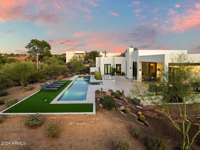 pool at dusk with a patio area