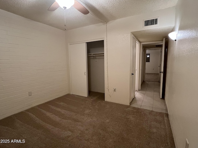 unfurnished bedroom featuring carpet floors, a closet, ceiling fan, visible vents, and a textured ceiling