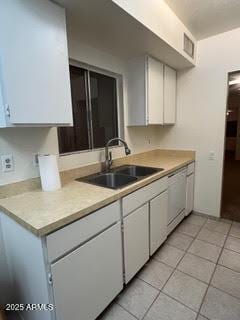 kitchen with light tile patterned flooring, dishwasher, light countertops, and a sink