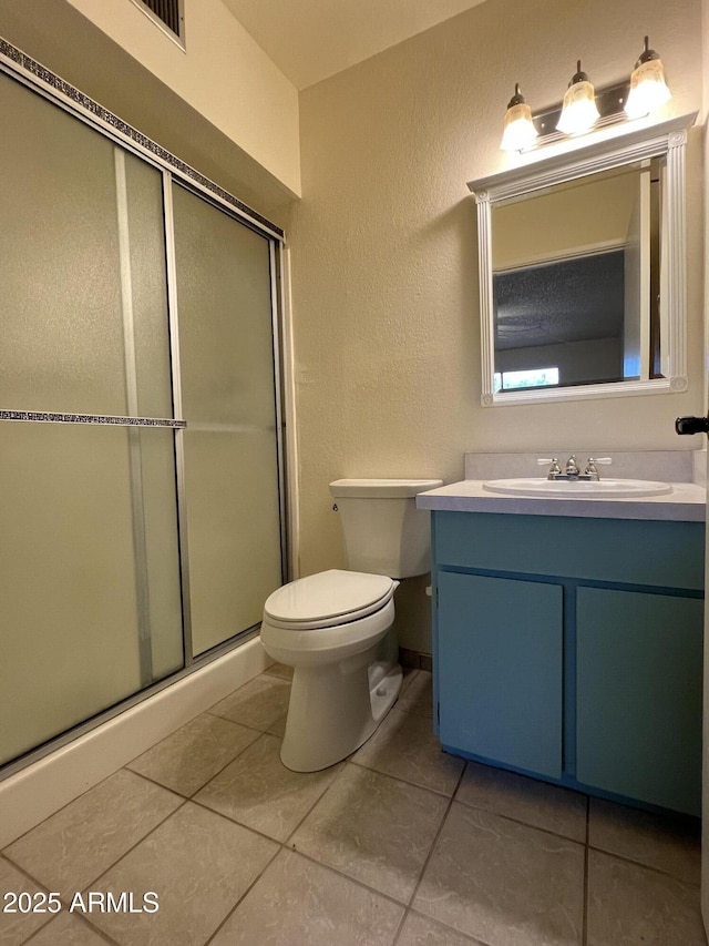 bathroom with tile patterned floors, a stall shower, toilet, and vanity