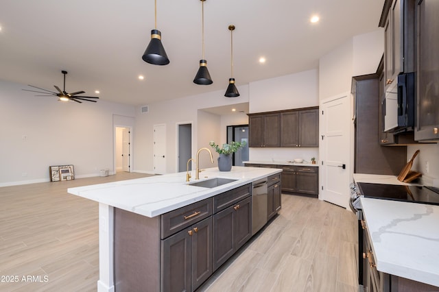 kitchen featuring stove, sink, decorative light fixtures, a center island with sink, and dishwasher