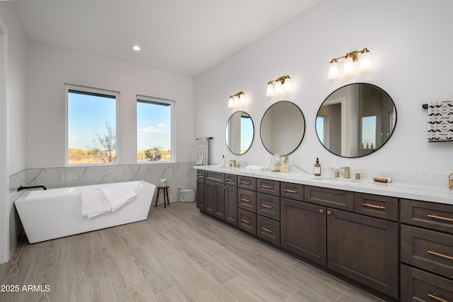 bathroom featuring a washtub, tile walls, and vanity