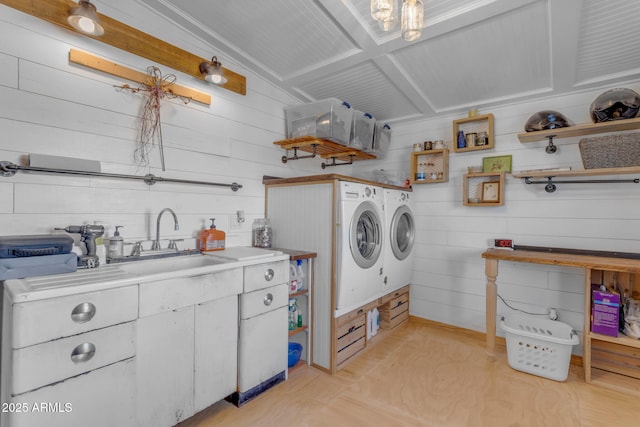 clothes washing area featuring washer and dryer, light wood-type flooring, and sink