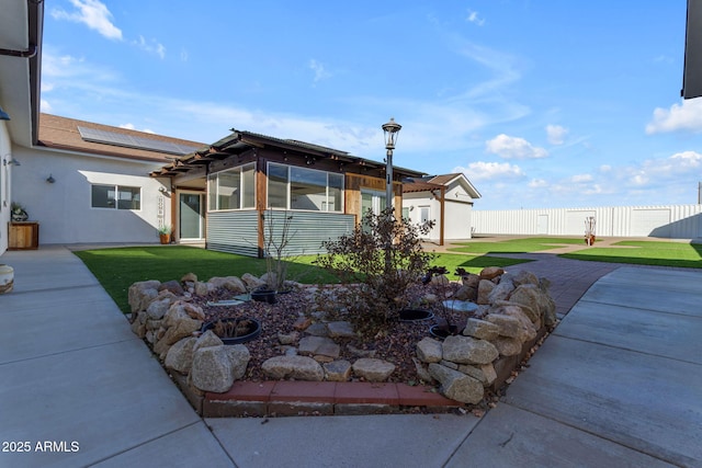 view of front facade featuring solar panels and a front lawn