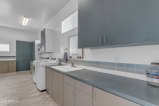 washroom with light wood-type flooring, cabinets, washing machine and clothes dryer, and sink