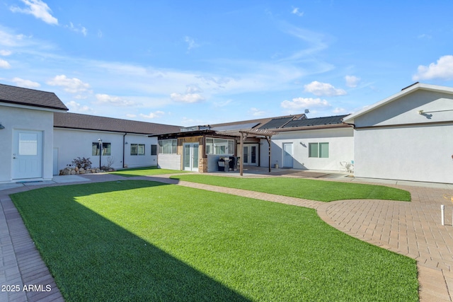 rear view of house featuring a lawn, a patio area, a pergola, and solar panels