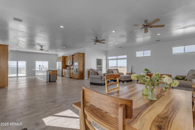 dining space featuring ceiling fan, light hardwood / wood-style flooring, and sink