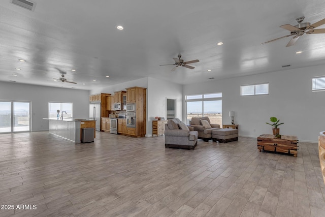 living room with sink, ceiling fan, and light hardwood / wood-style floors