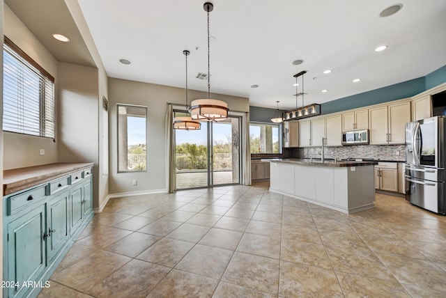 kitchen with pendant lighting, stainless steel appliances, a wealth of natural light, and an island with sink