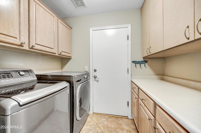 washroom featuring washer and dryer, light tile patterned flooring, and cabinets